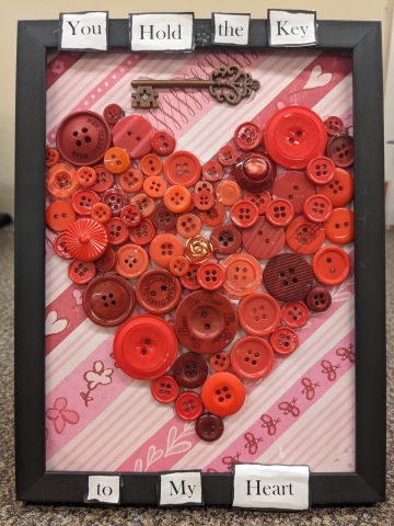 Black frame red buttons forming a heart. Reads "you hold the key to my heart".