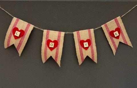 Stripped burlap banner with red hearts and the letters L O V E on a gray background.