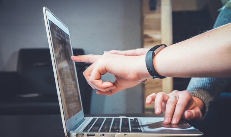 open laptop with people pointing at the screen