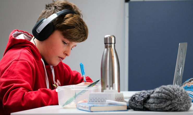 Teen boy doing homework with headphones on