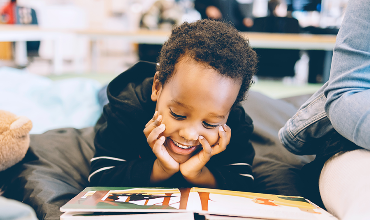 Young boy looking through picture book and smiling