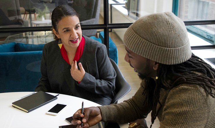 Woman talking to man at a small meeting room table